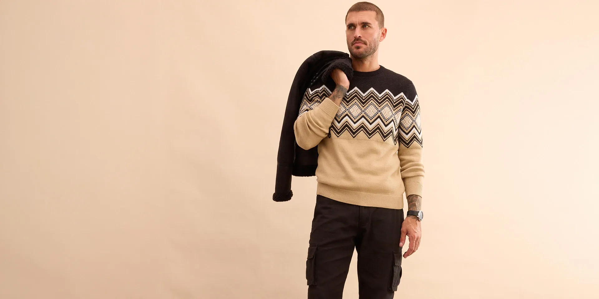 Stilfull look med sort vinterjakke, mønstret genser og jeans for kalde dager.