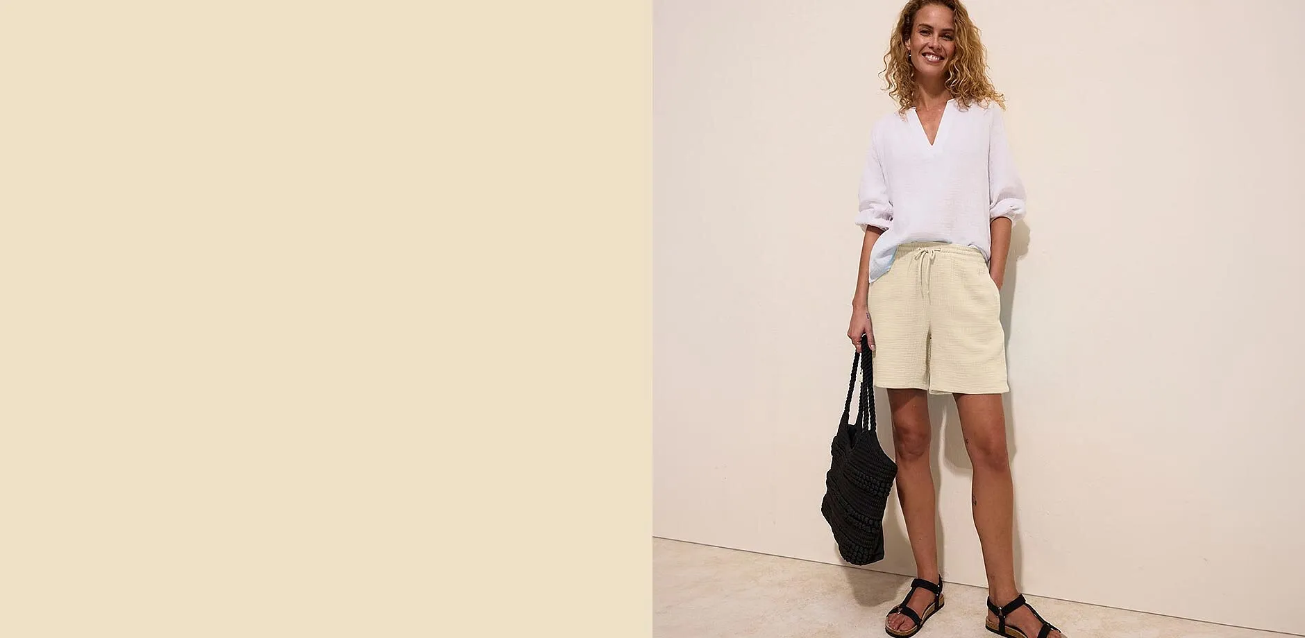 Hvit bluse, beige musselinshorts og sorte sandaler for en avslappet sommerstil.