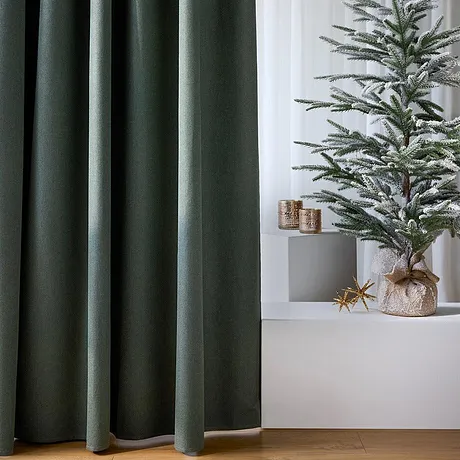 Mørke gardiner rammer inn det festlige juletreet.