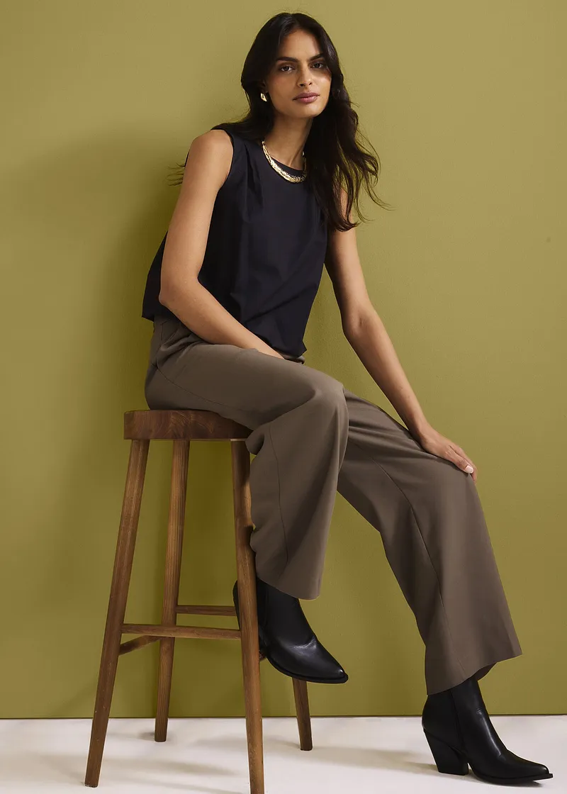 Mørkeblå, ermeløs topp, vid, brun bukse og sorte skoletter. Elegant, ledig look.