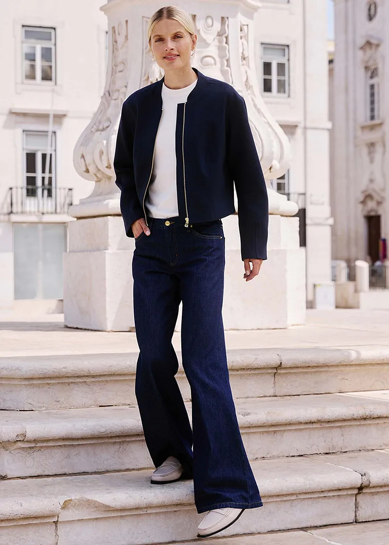 Elegant look med mørk jakke, hvit topp og vide jeans.