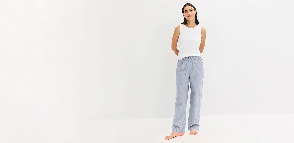 Ledig pyjamaslook: Hvit, ermeløs topp kombinert med stripete, luftig bukse for en avslappet, elegant stil.