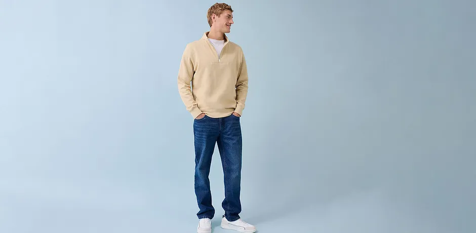 Ledig look med kremfarget genser, blå jeans og hvite sneakers.
