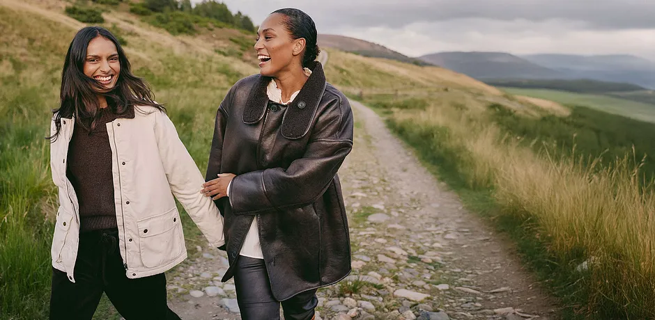 Elegant, brun skinnkåpe med stor krage kombinert med en lys topp og mørk bukse.