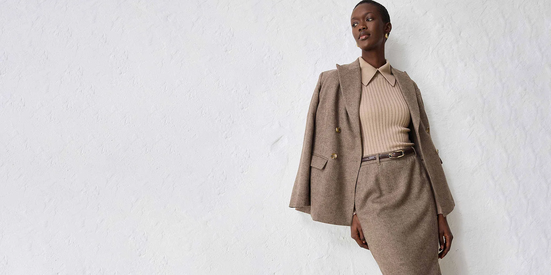 Beige blazer med passende, strikket genser og skjørt.