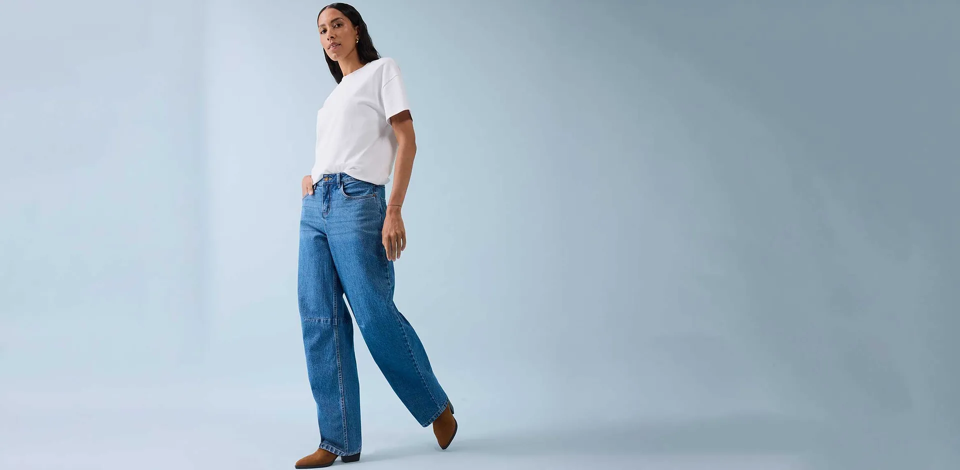 Klassisk hvit T-skjorte kombinert med vide jeans og brune sko.