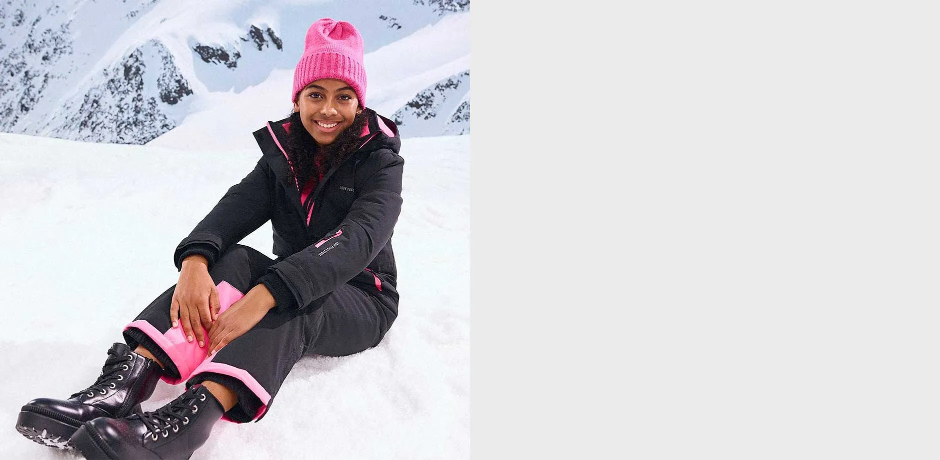 Sort vinterjakke og bukse, pink lue.