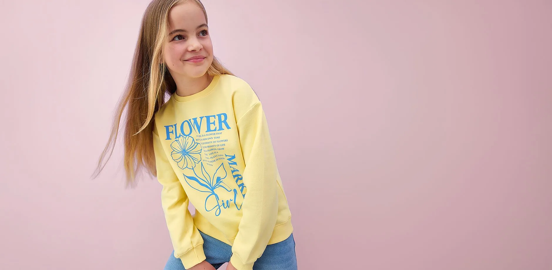 Gul, langermet topp med blomsterm&oslash;nster og bluejeans.