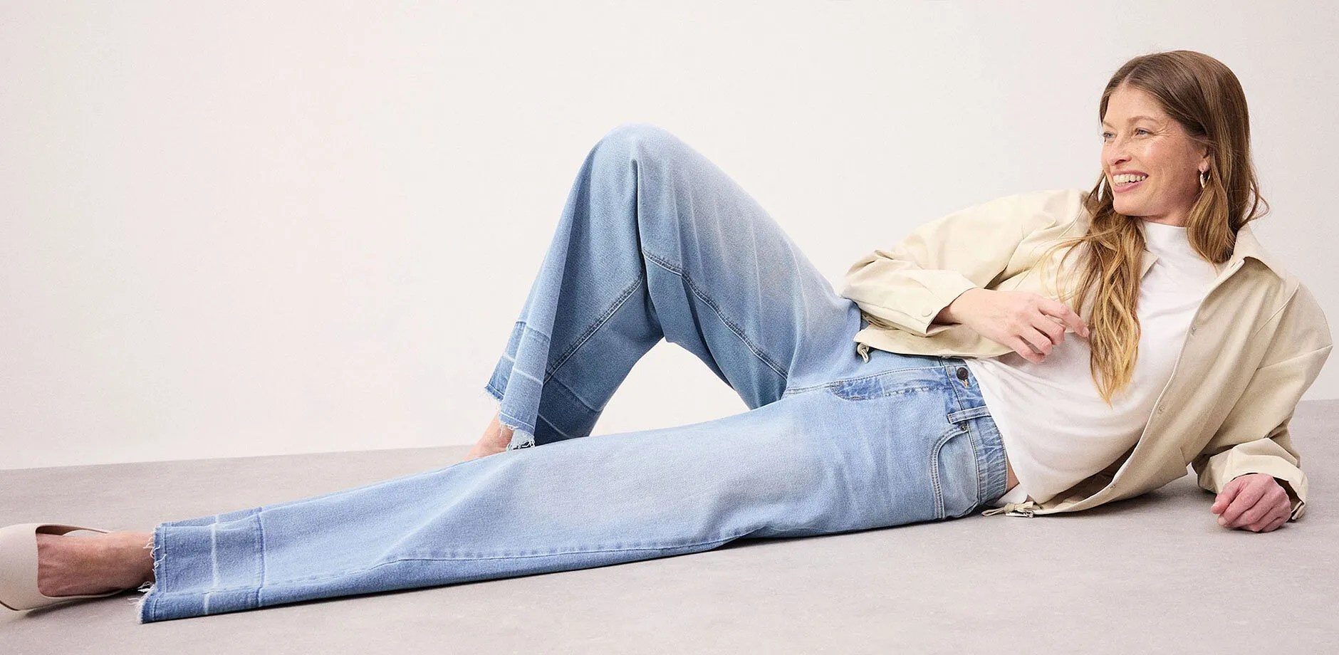 Avslappet look best&aring;ende av vide jeans, hvit topp og beige jakke.