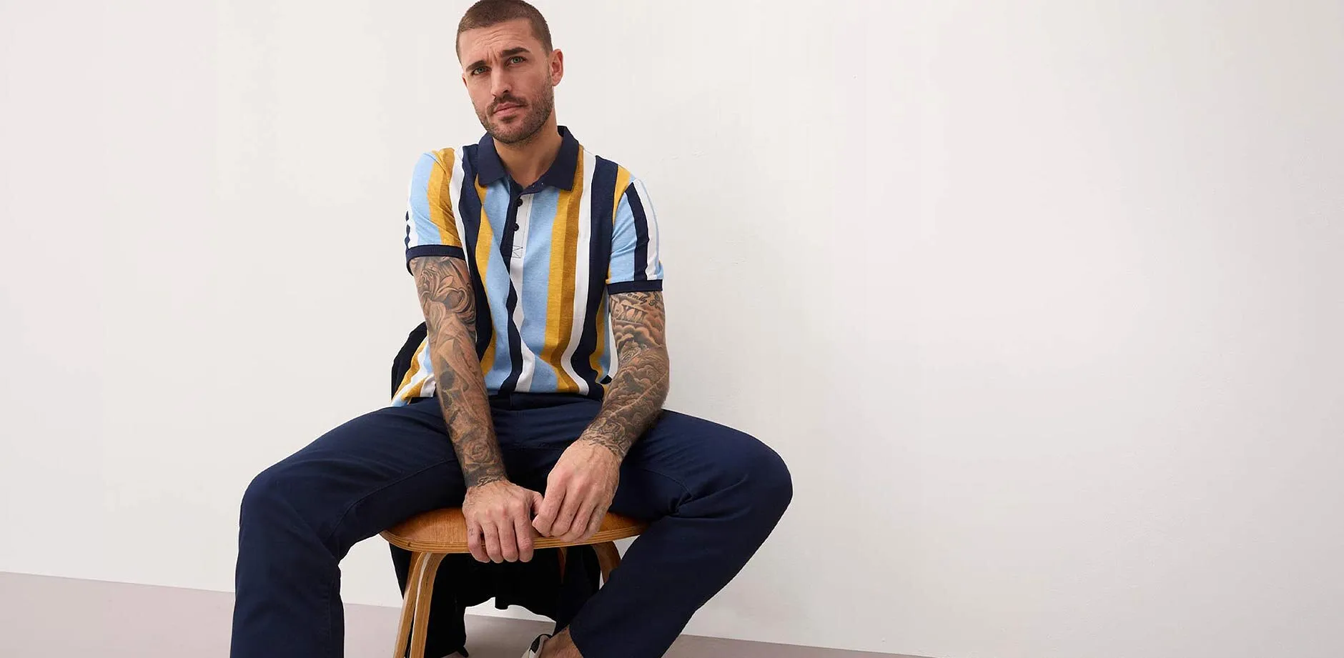 Stripete pik&eacute;skjorte og m&oslash;rkebl&aring; bukse.