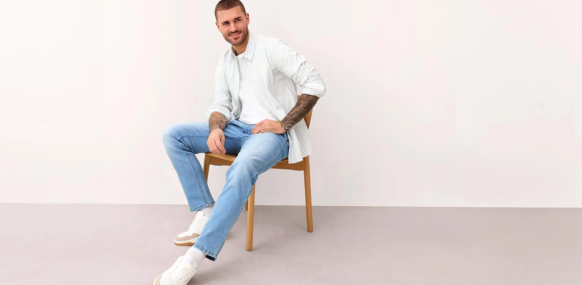 Hvit, stripete skjorte, lysebl&aring; jeans og hvite sneakers.