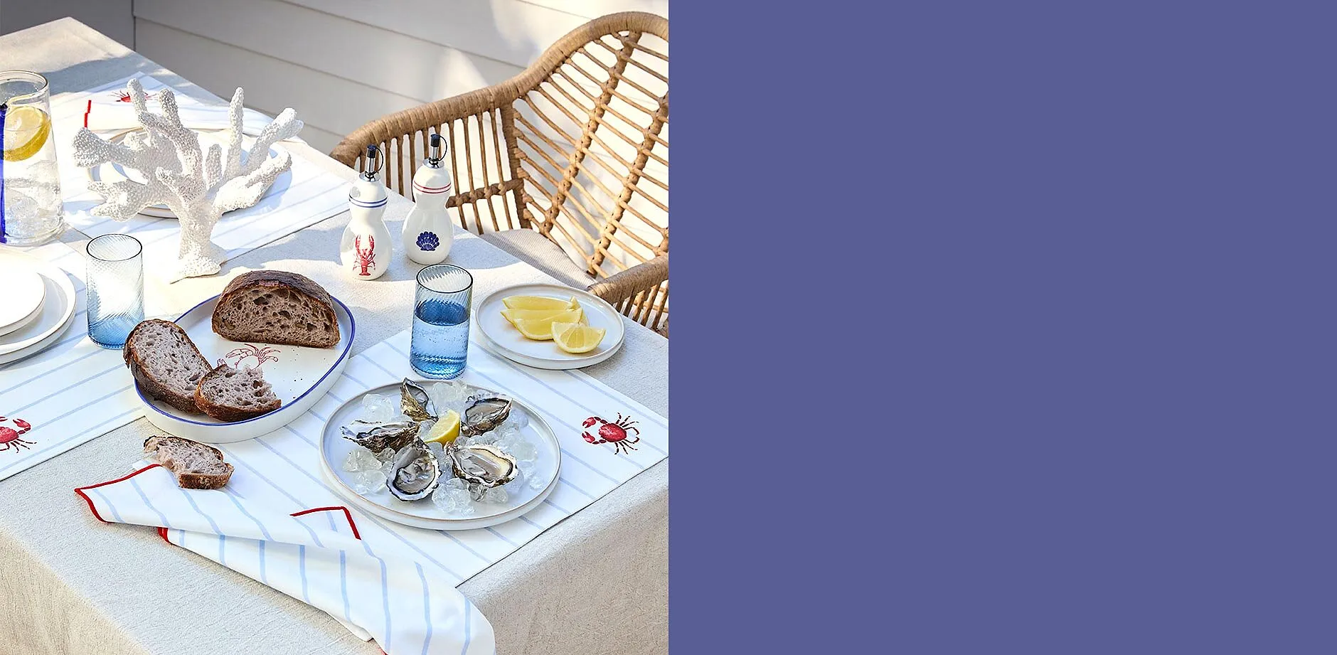 Elegant, hvit duk med r&oslash;de broderier pryder sommerbordet for en piknik i det fri.