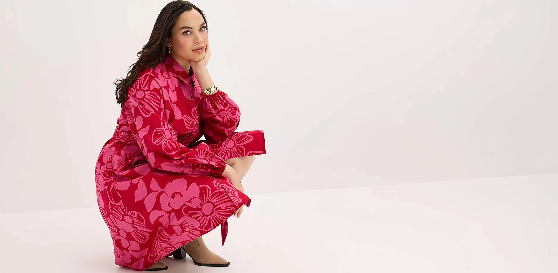 I&oslash;ynefallende, r&oslash;d kjole med blomsterm&oslash;nster, lange ermer og krage.