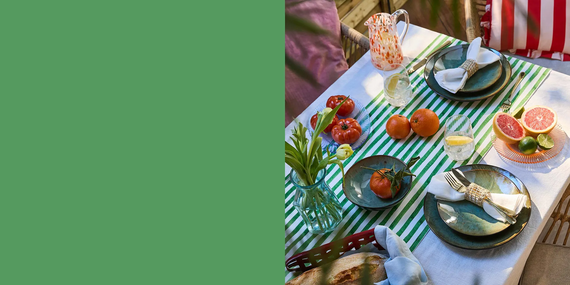 En stripete duk pynter sommerbordet dekket med flerfarget servise og fersk frukt.