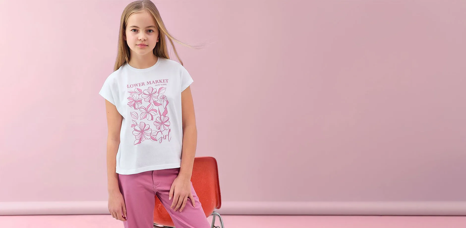 Hvit T-skjorte med rosa trykk og rosa bukse.