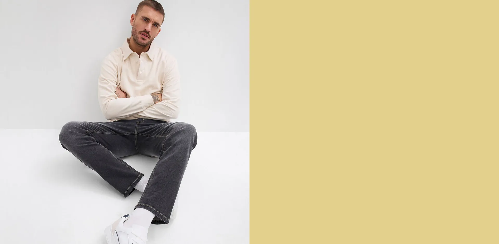 Mann i kremfarget shirt, m&oslash;rkegr&aring; bukse og hvite sneakers.