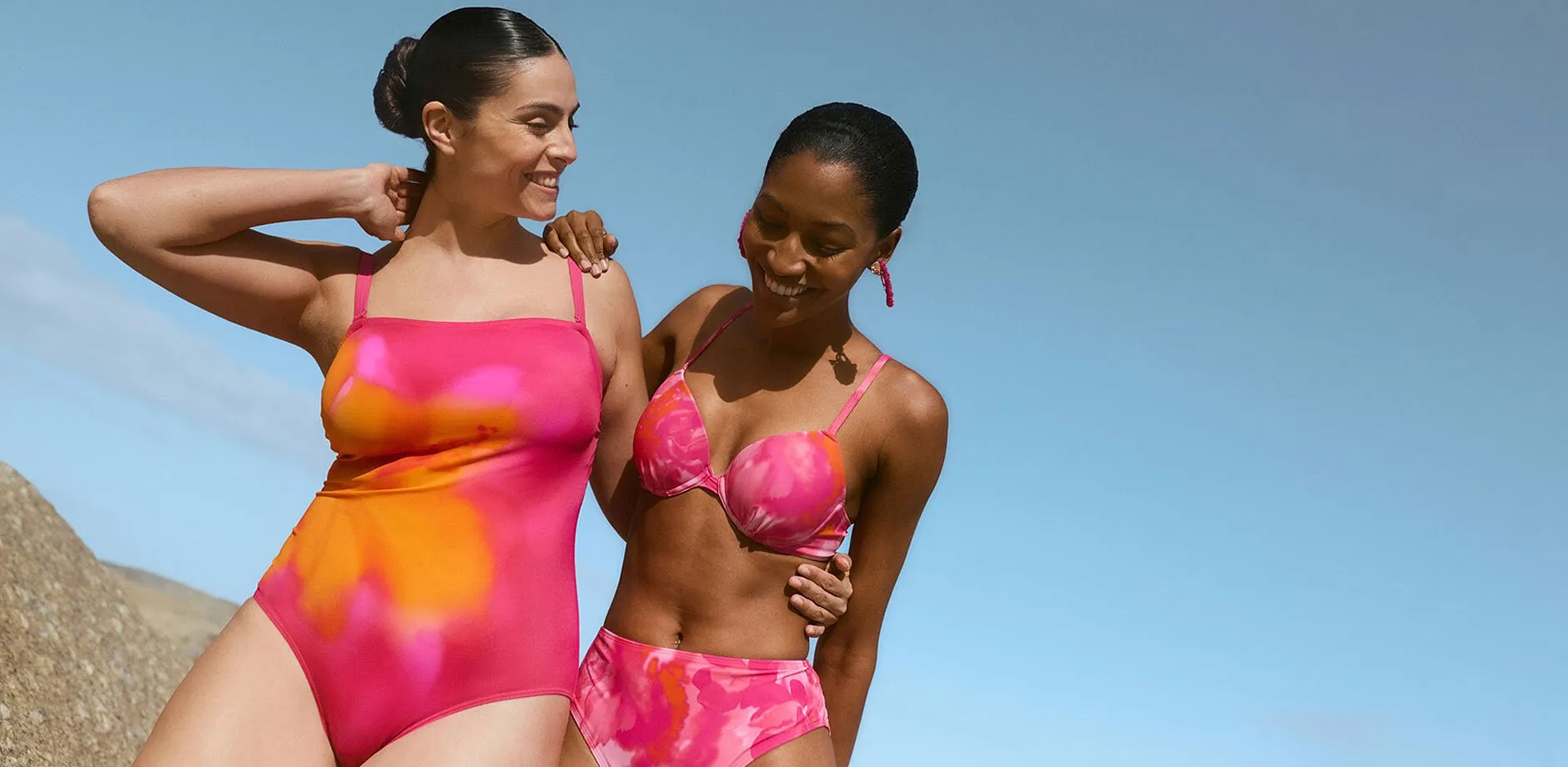 To personer i lysende rosa badedrakt og bikini p&aring; stranden.