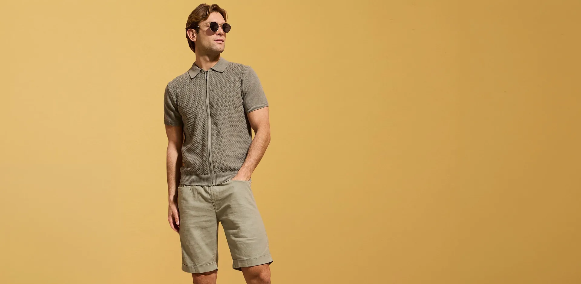Gr&aring;, strikket poloskjorte med glidel&aring;s og beige shorts for en uformell sommerstil.