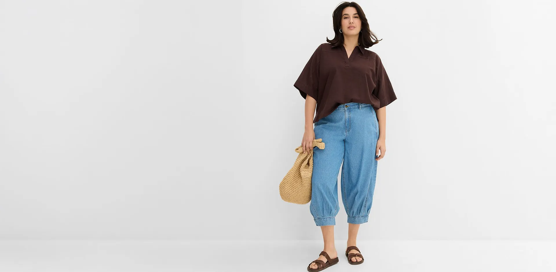 Antrekk best&aring;ende av brun bluse og vide jeans med sandaler og str&aring;veske.