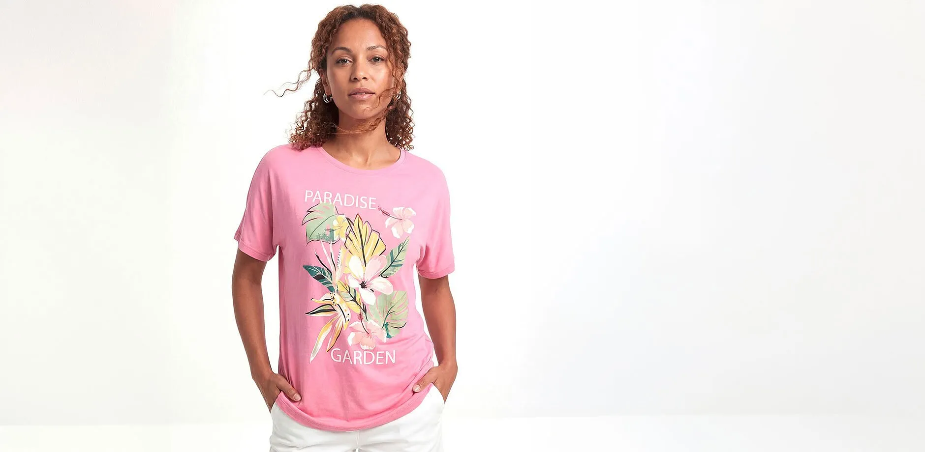 Rosa T-skjorte med blomstermotiv og hvit bukse.