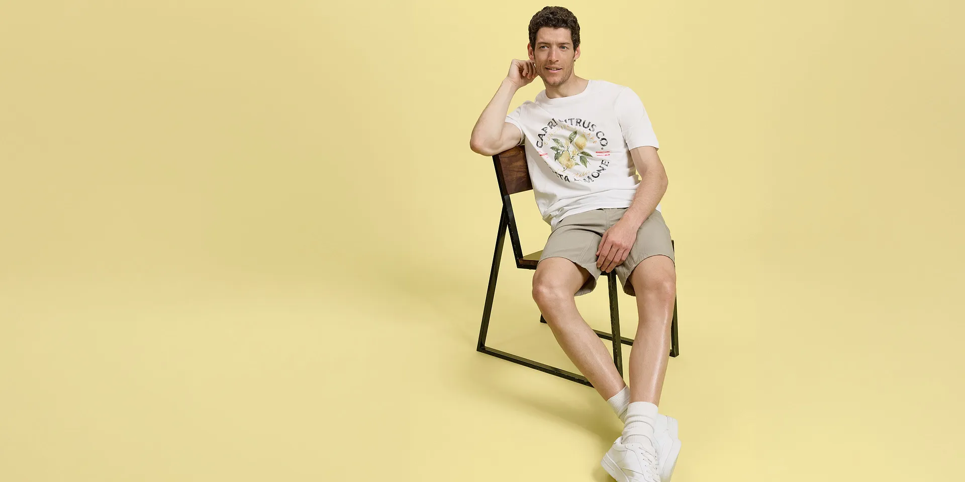 Sommerlook med beige shorts, hvit T-skjorte og behagelige sneakers.