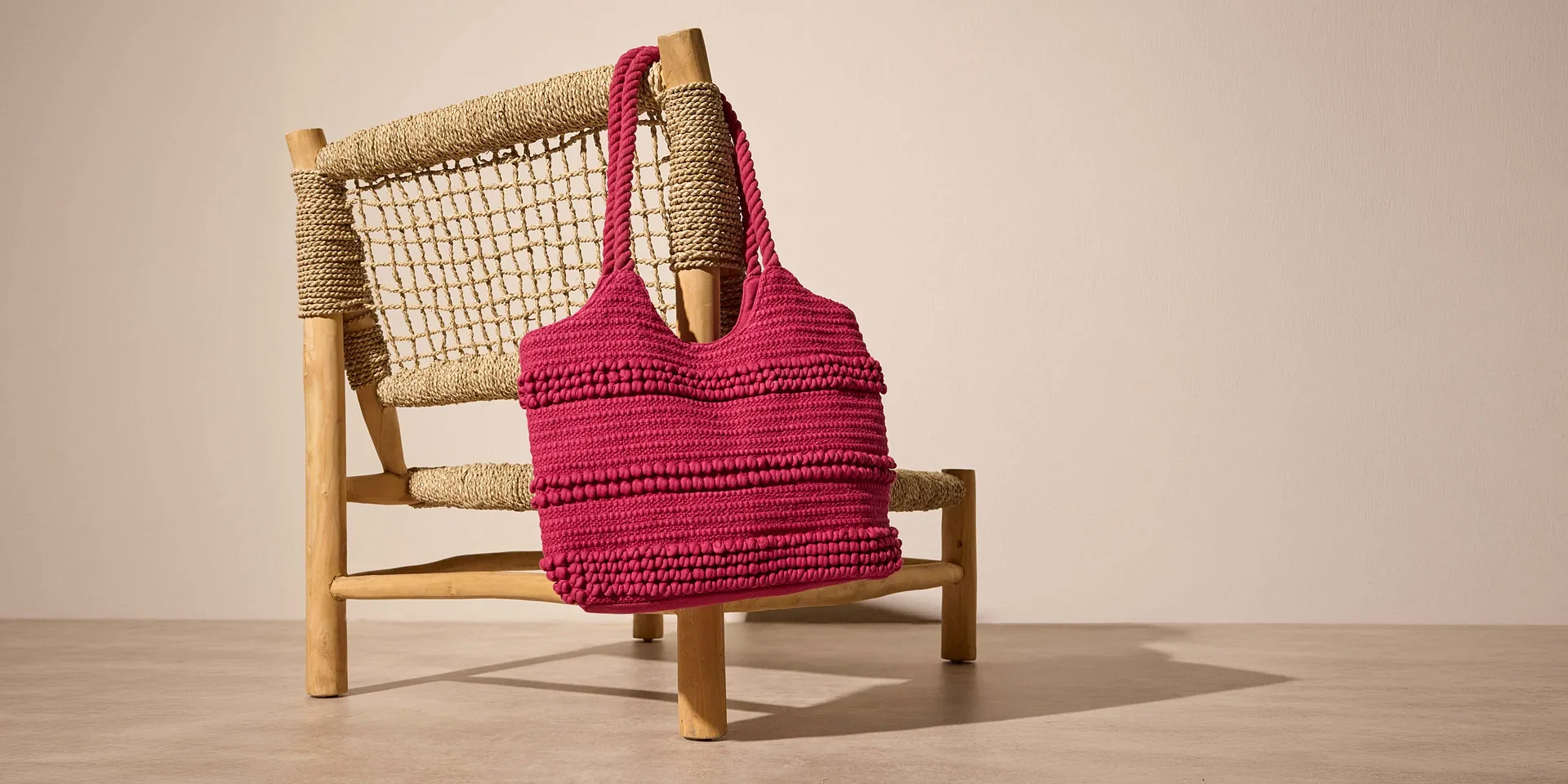 Rosa, heklet veske med strukturert overflate.