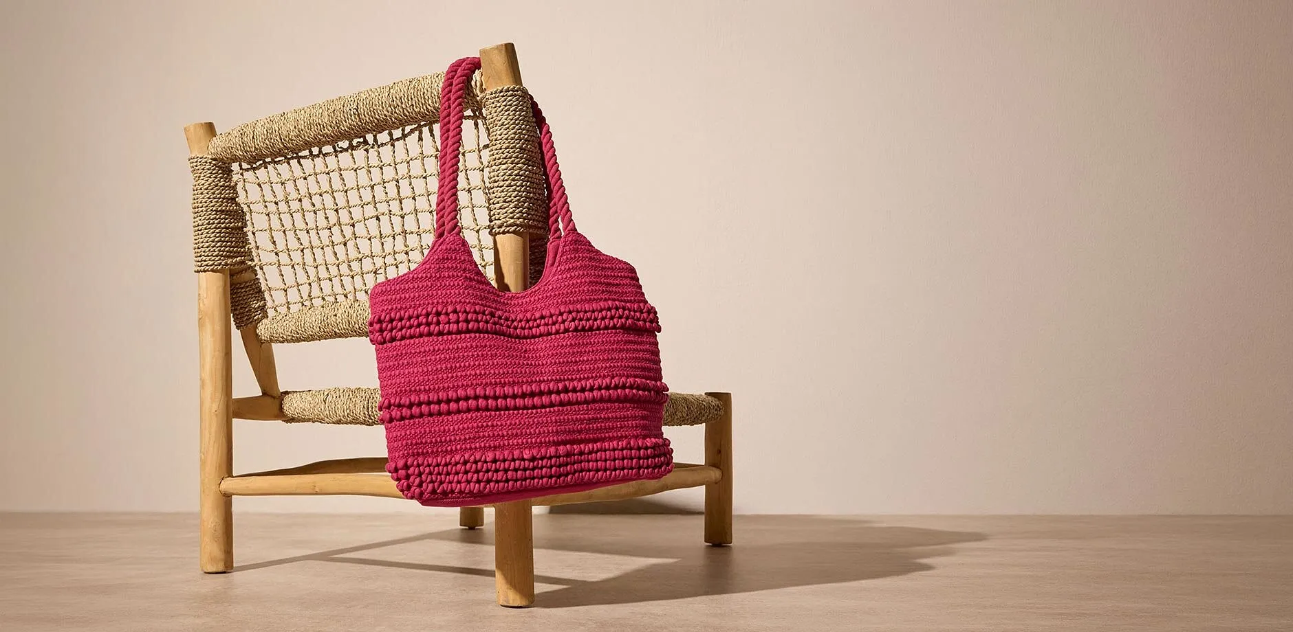 Rosa, heklet veske i strukturert materiale.