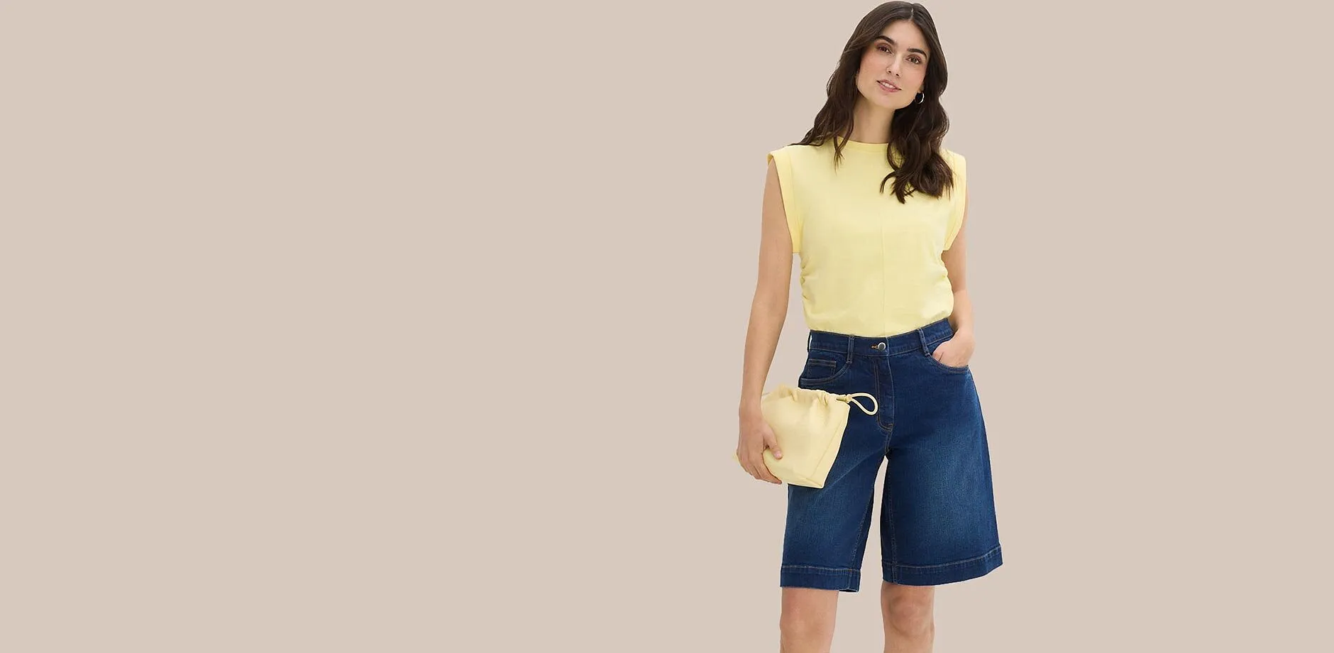 Gul topp med skulderputer, bermudashorts i denim og matchende poseveske.