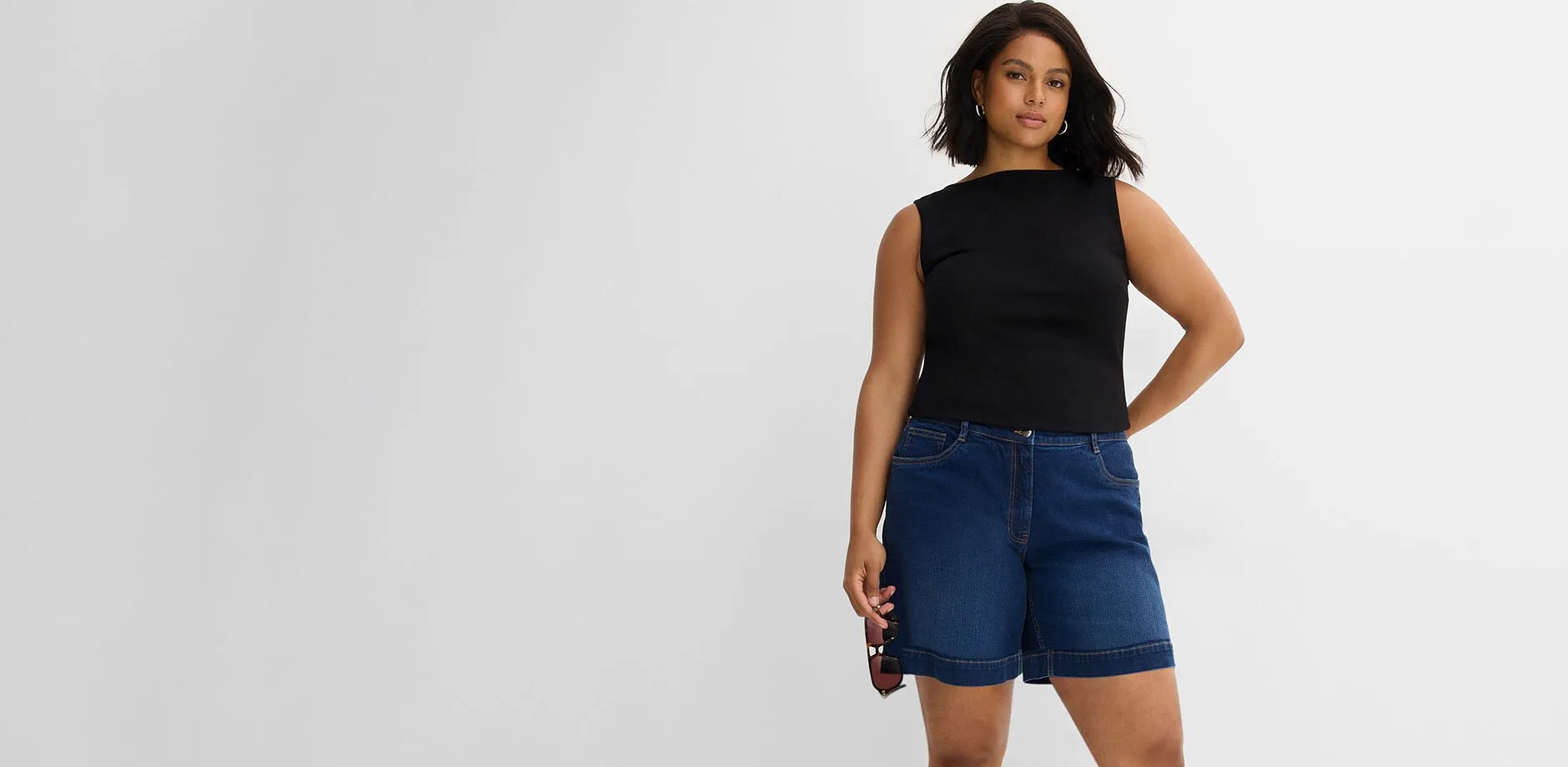 Sort singlet og avslappet, bl&aring; denimshorts.