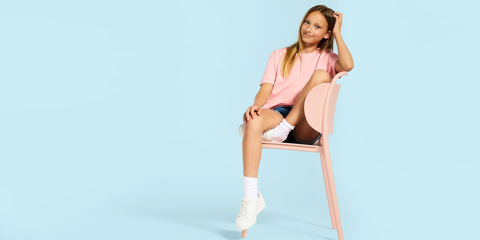 Rosa T-skjorte, korte jeans, hvite sokker og joggesko.