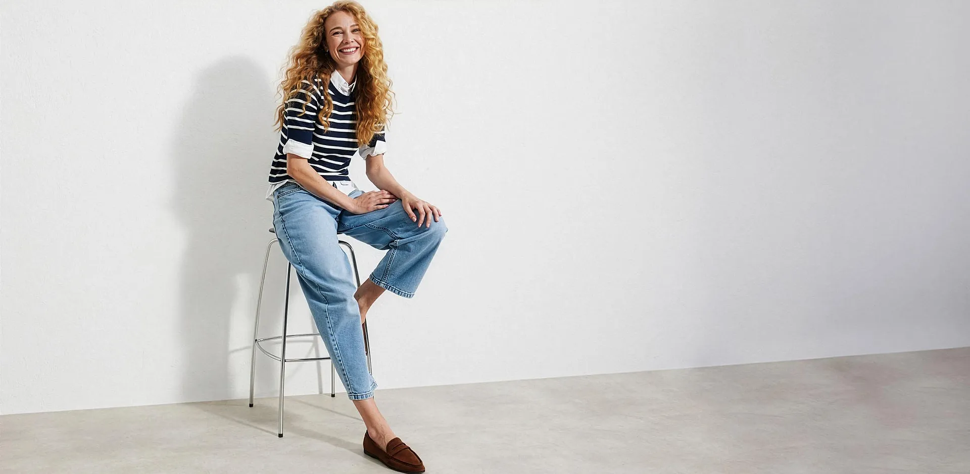 Stripete genser over bluse, lyse jeans og brune loafers.