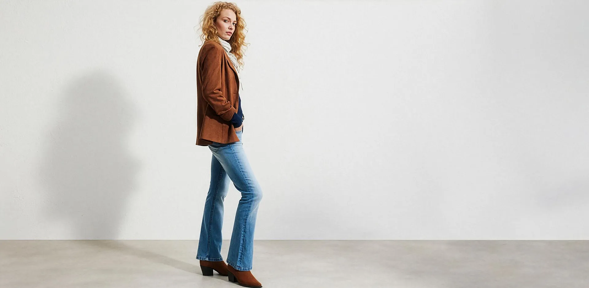 Brun jakke i semsket skinn, avslappede, flared jeans, hvit topp og brune ankelst&oslash;vletter.
