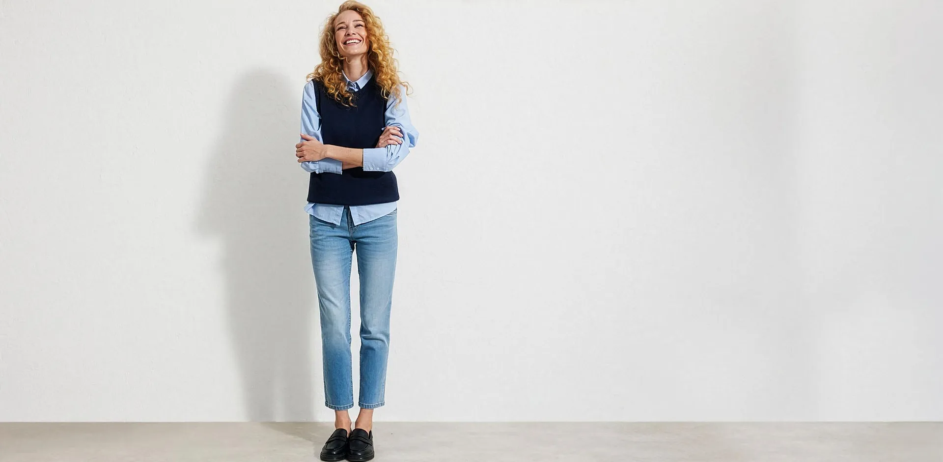 Lysebl&aring; skjorte, m&oslash;rkebl&aring; vest, bluejeans og sorte loafers.
