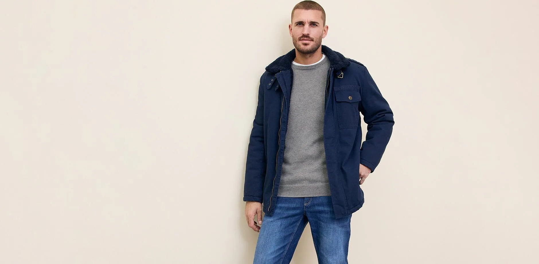 M&oslash;rkebl&aring; jakke over gr&aring; genser kombinert med bluejeans.