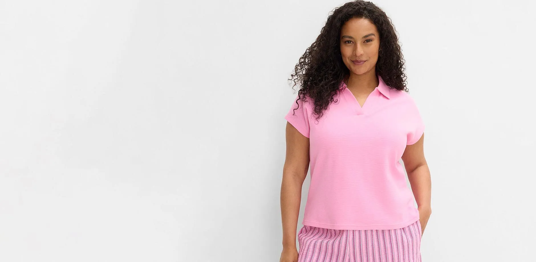 Kortermet, rosa topp med krage og stripete bukse.
