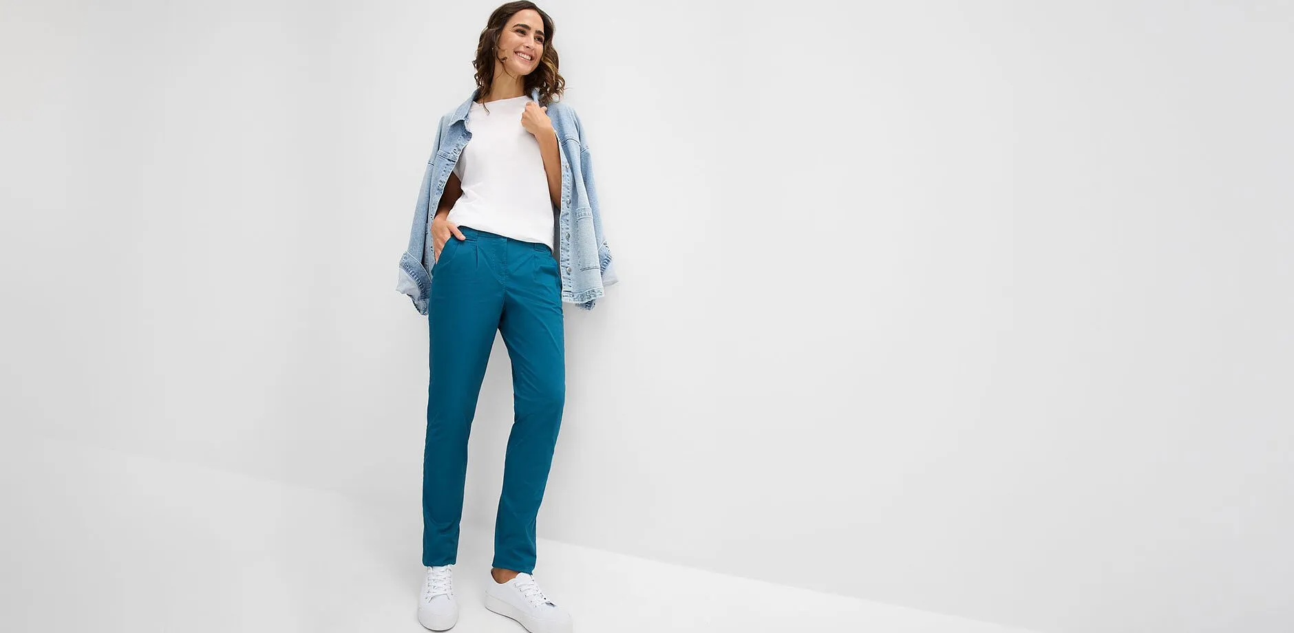 Turkis bukse, hvit topp, avslappet denimjakke og hvite sneakers.
