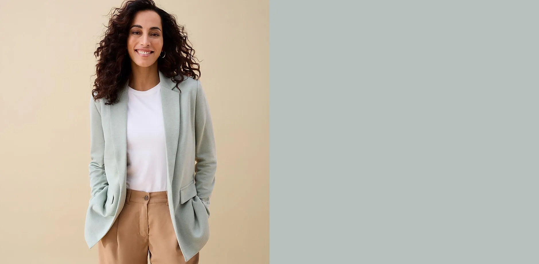 Person i mintgr&oslash;nn blazer, hvit topp og brun bukse.
