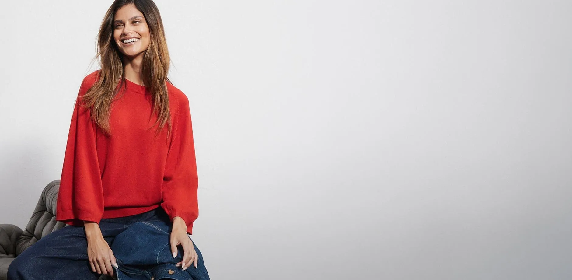 R&oslash;d genser med vide ermer kombinert med bluejeans og jakke i denim.