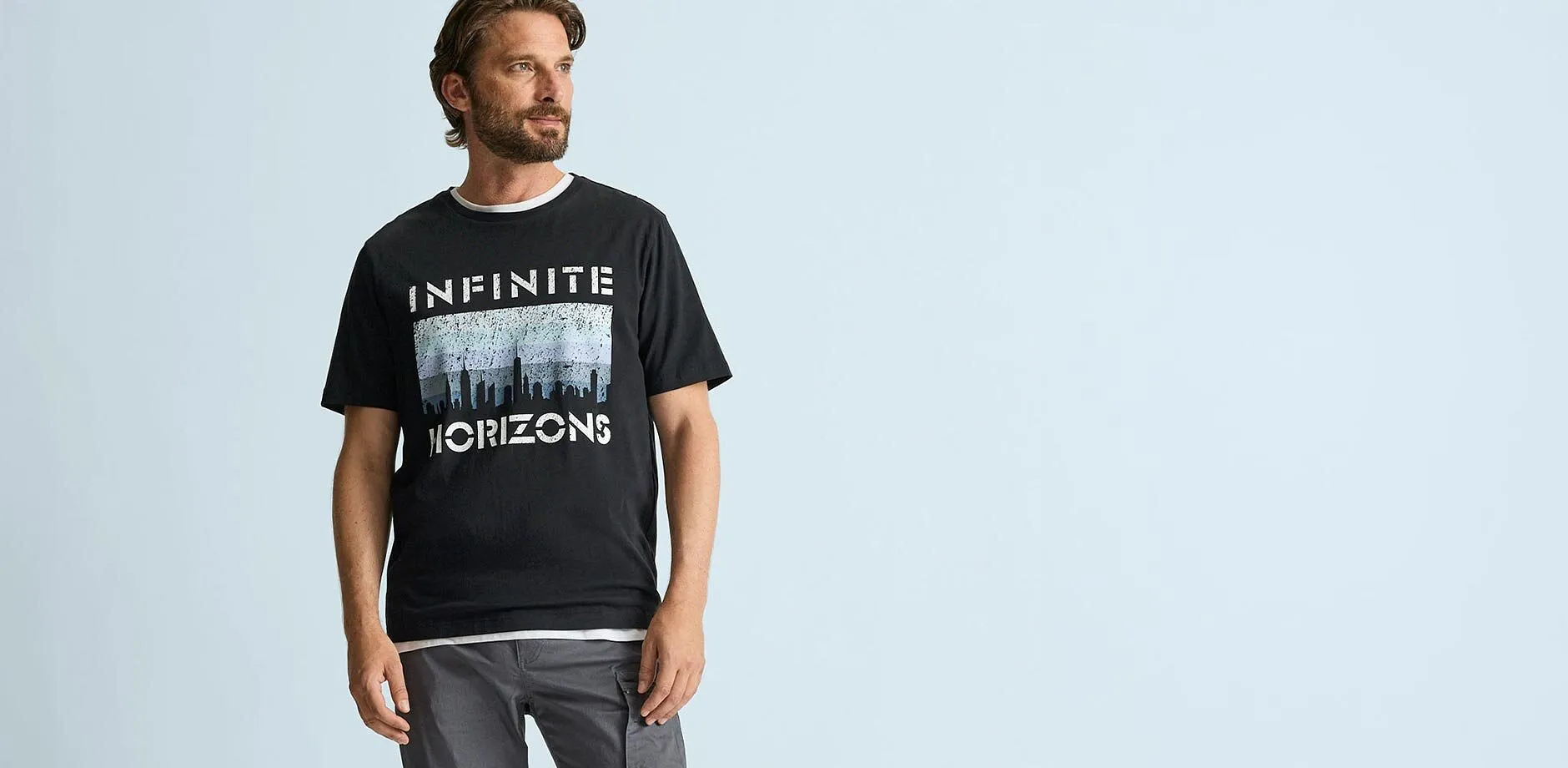 Sort T-skjorte med &laquo;Infinite Horizons&raquo;-trykk og behagelig, gr&aring; cargobukse.