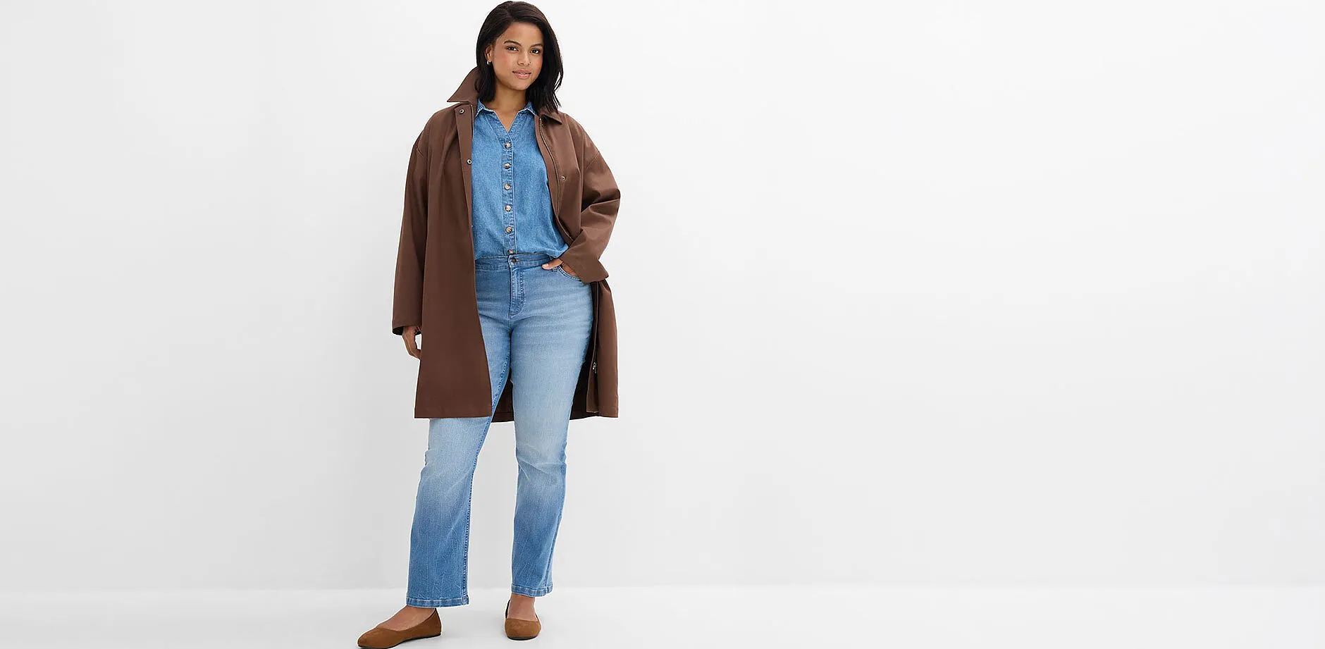 Brun k&aring;pe over denimskjorte, lyse jeans og behagelige, brune sko.