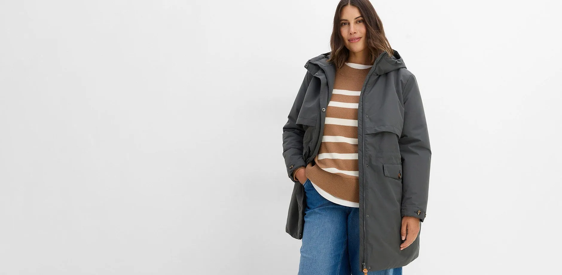 Gr&aring; funksjonsjakke, stripete genser og behagelige jeans.