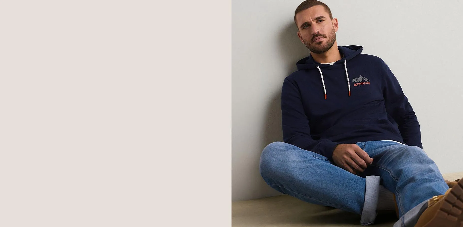 Hen kledd i m&oslash;rkebl&aring; hettegenser med fjellmotiv og avslappede, bl&aring; jeans.
