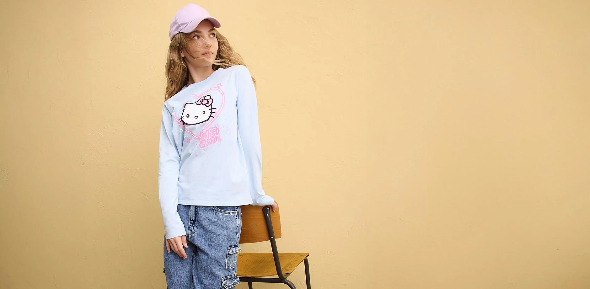 Bl&aring;, langermet topp med Helly Kitty-trykk, bluejeans og rosa caps.