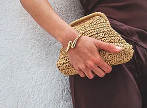 Elegant brun kjole møter sommerlig stråclutch. Gullarmbånd som stilig detalj.