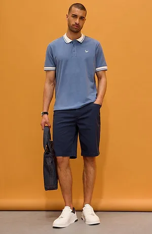 Lyseblå poloskjorte med hvit krage og mørke bukser. En sporty og elegant hverdagsstil.