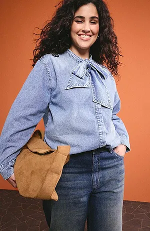Lyseblå denimbluse med sløyfe­krage, mørke jeans og brun skinnveske for en avslappet hverdagslook.