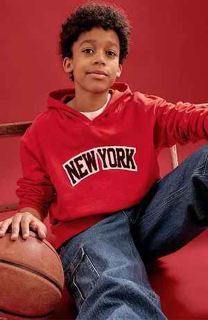 Rød hettegenser med New York-skrift og blå jeans.