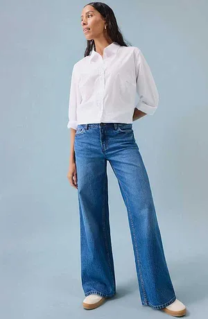 Hvit skjorte kombinert med blå slengbukse i denim og hvite sko.