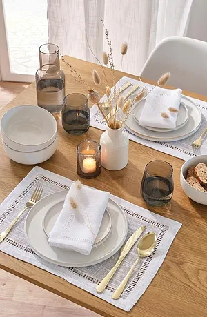 Elegant bordduk med blondemønster, hvite tøyservietter og gullfarget bestikk sørger for stilfulle aksenter.