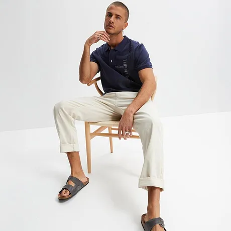 Mørkeblå poloskjorte med hvit bukse og grå sandaler. Ledig sommerlook for hver dag.